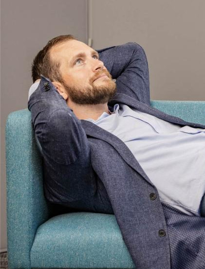 Smartly dressed, Andrew reclines on couch after successfully navigating a career pivot